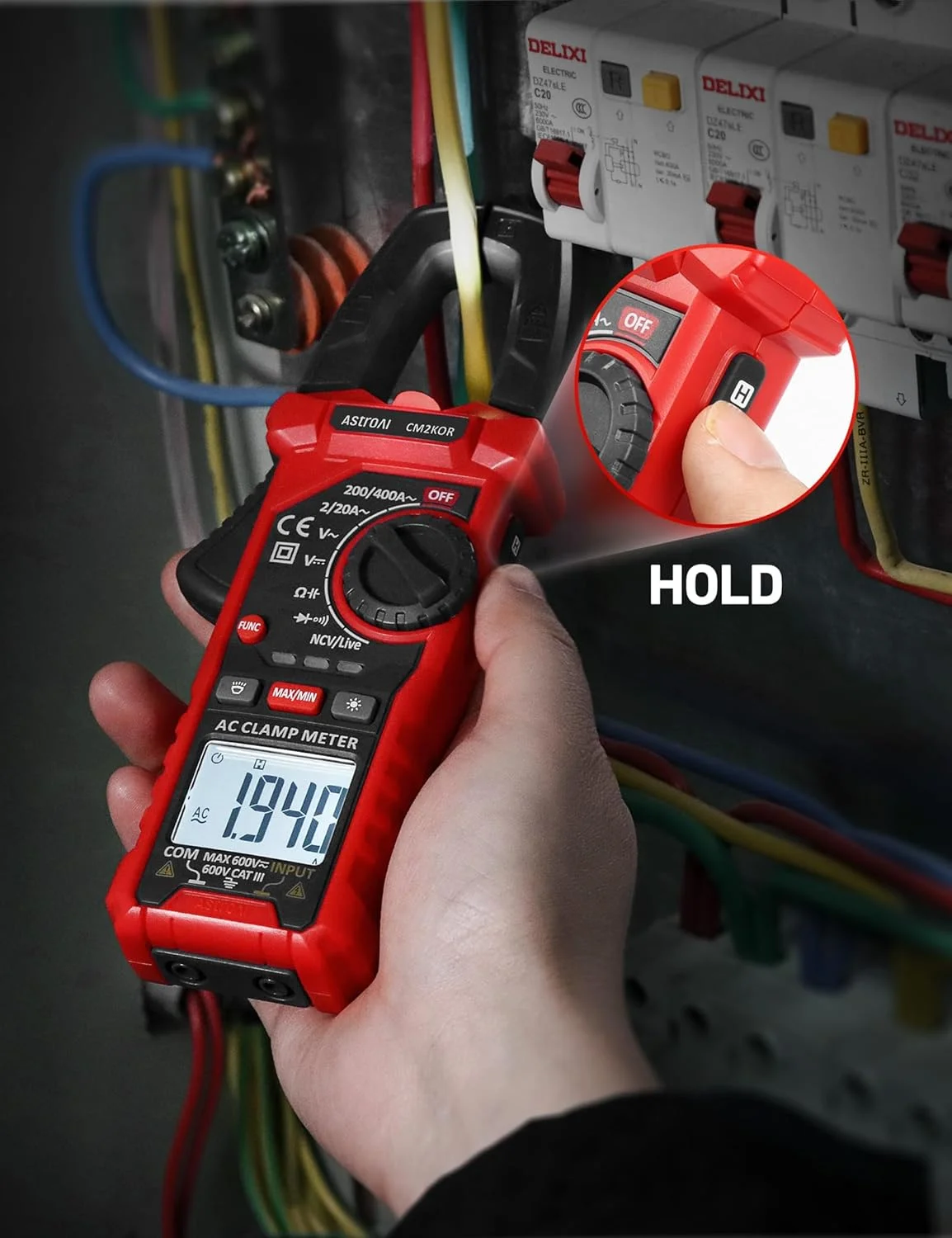 A hand using the clamp jaw around a yellow wire inside an electrical box while demonstrating the use of the data hold button on the side.